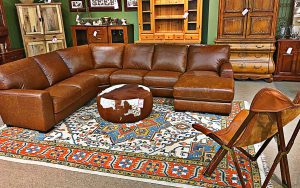 A living room with brown leather furniture and a rug.