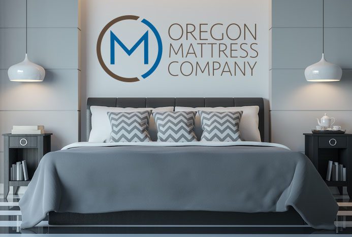 A bed with pillows and a mattress in front of the logo.