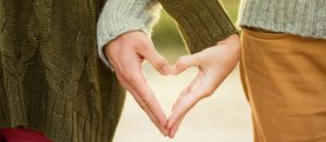 A man and woman making heart with their hands.